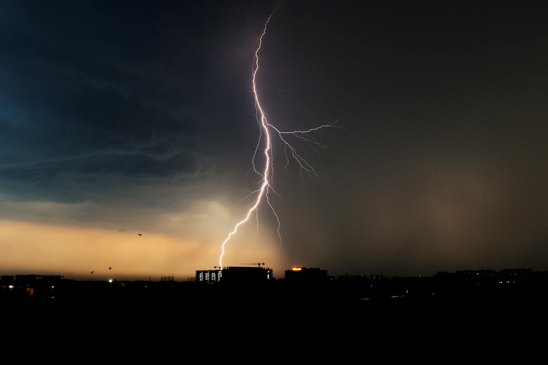 Striking lightning bolt during a storm over Chandigarh city skyline at dusk.